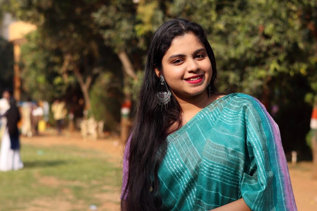 Smiling woman in traditional Indian saree enjoying a sunny day in Bhubaneswar park.